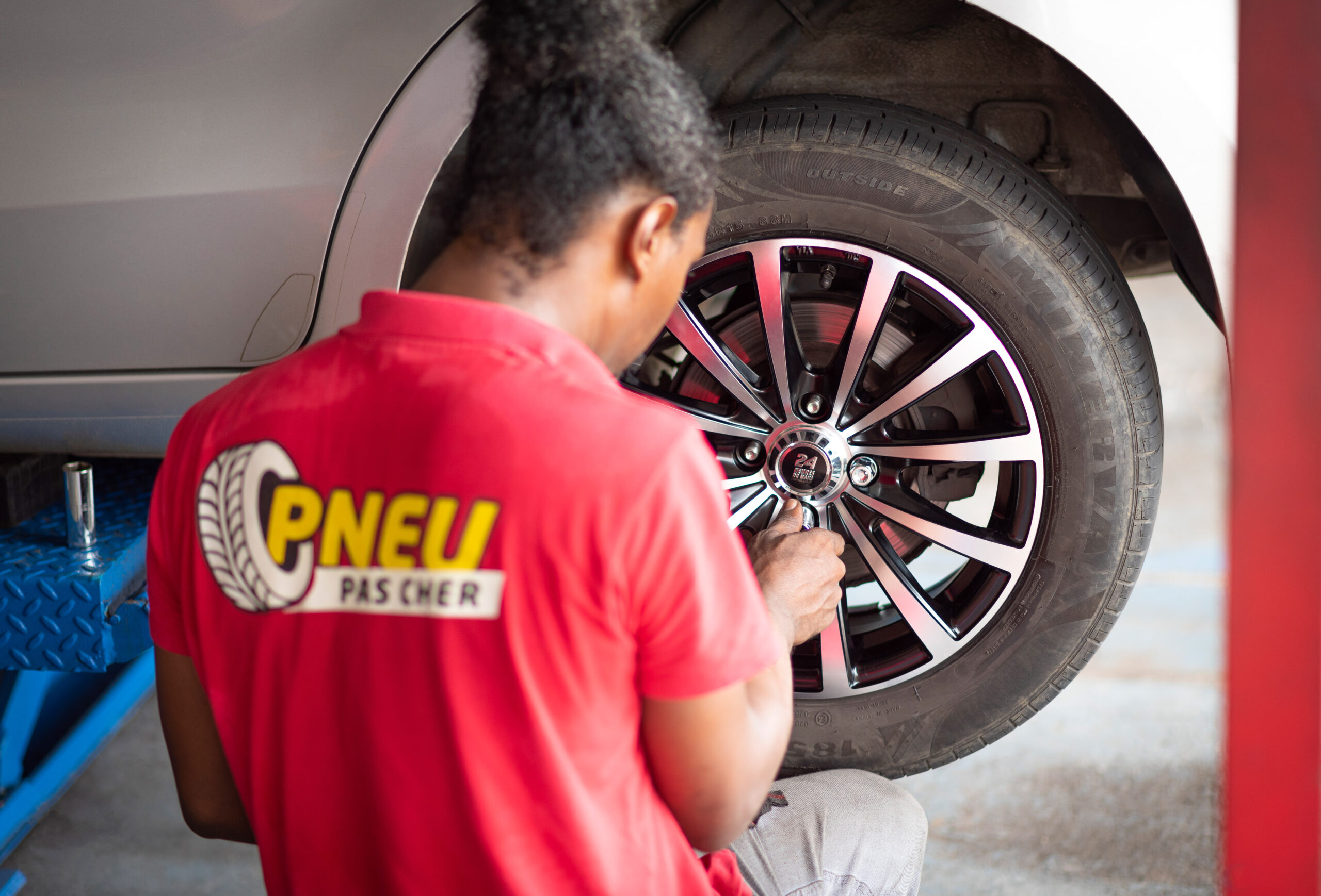 Technicien Pneu Pas Cher réalisant le montage et le serrage d'une roue de voiture dans le centre de Bochette