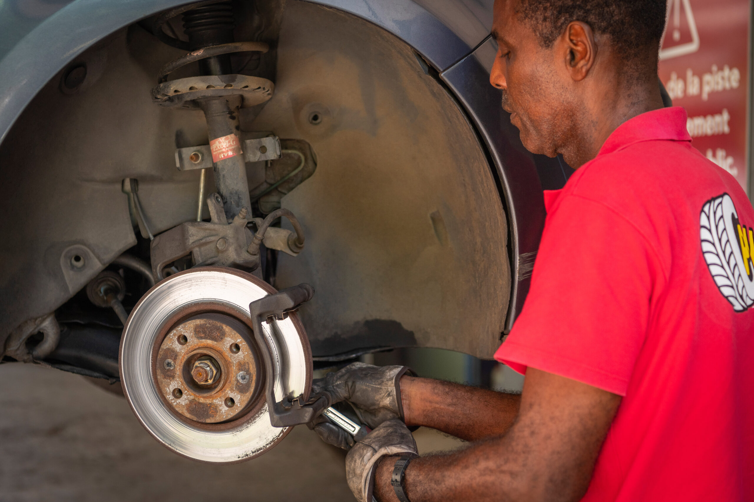 Employé Pneu Pas Cher vérifiant le système de freinage et les disques de frein d'un véhicule au centre de Case-Pilote