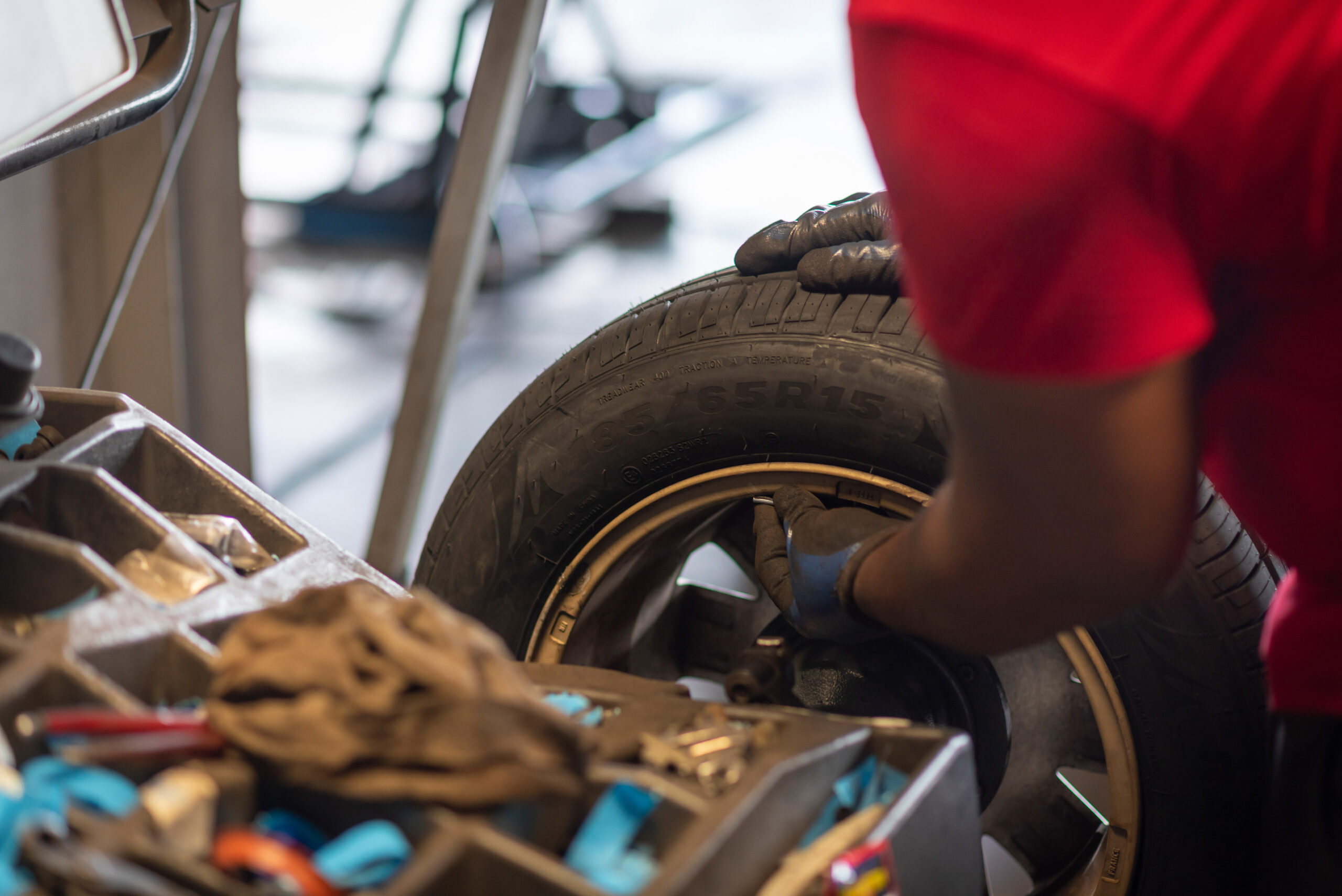 Mécanicien Pneu Pas Cher manipulant une roue sur une machine professionnelle pour l'équilibrage des pneus au centre de Place d'Armes